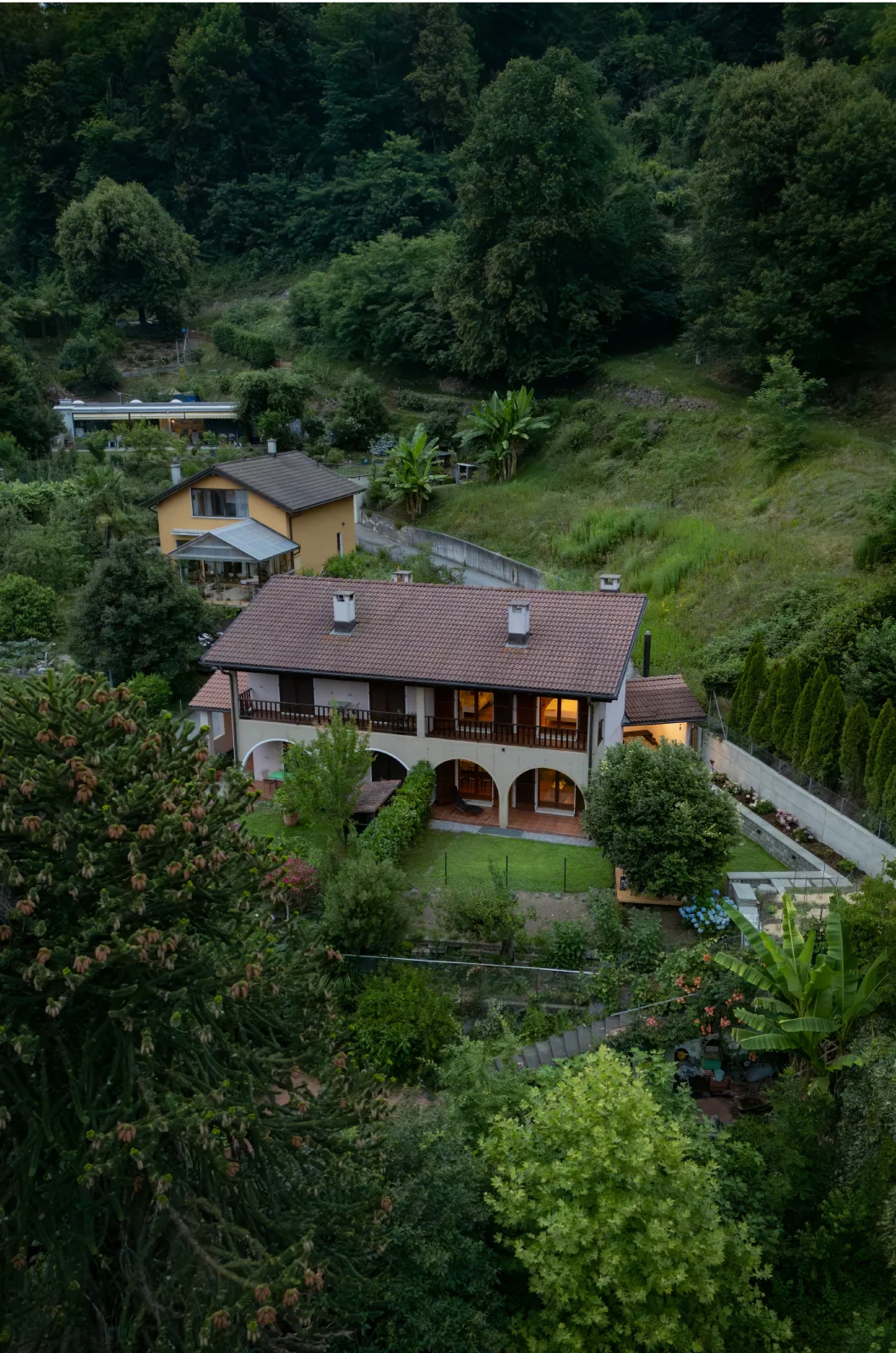 Casa Ortensia seen from above, surrounded by the green hills of the Malcantone in Ticino